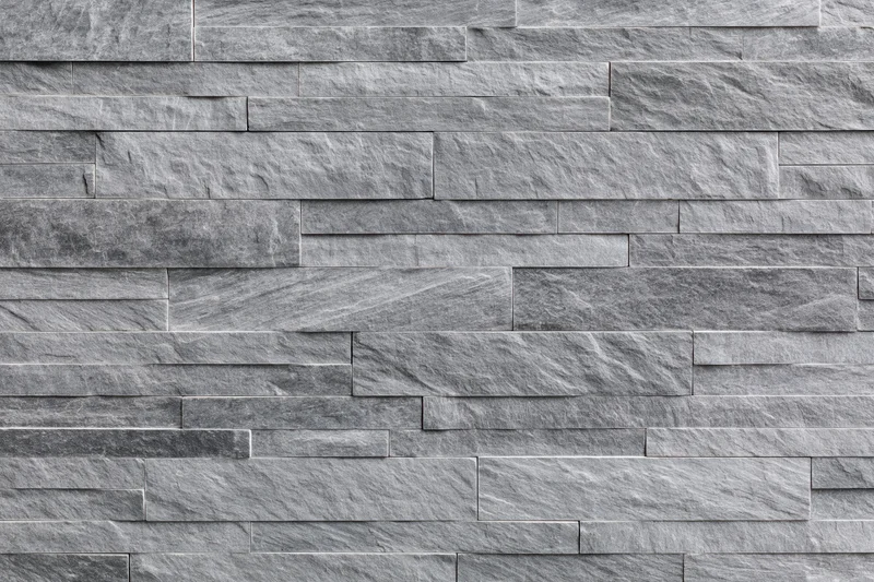 Stacked slate stone wall with horizontal rectangular tiles forming a textured gray surface