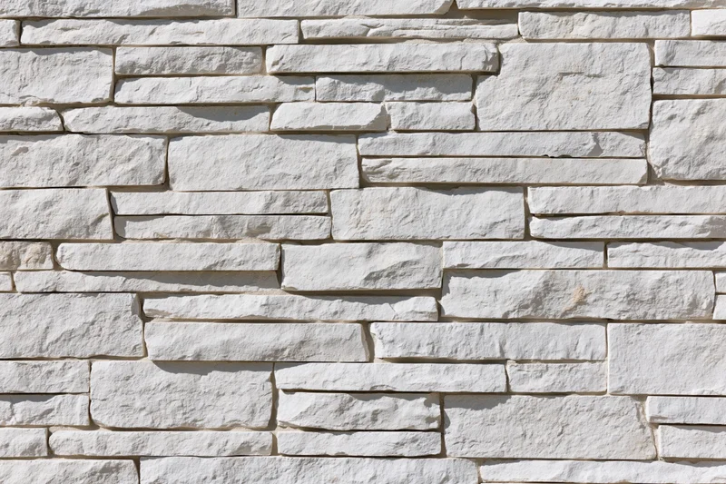 Close-up of white stacked stone wall with irregular horizontal pattern