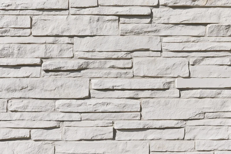 Close-up of white stacked stone wall with irregular horizontal pattern
