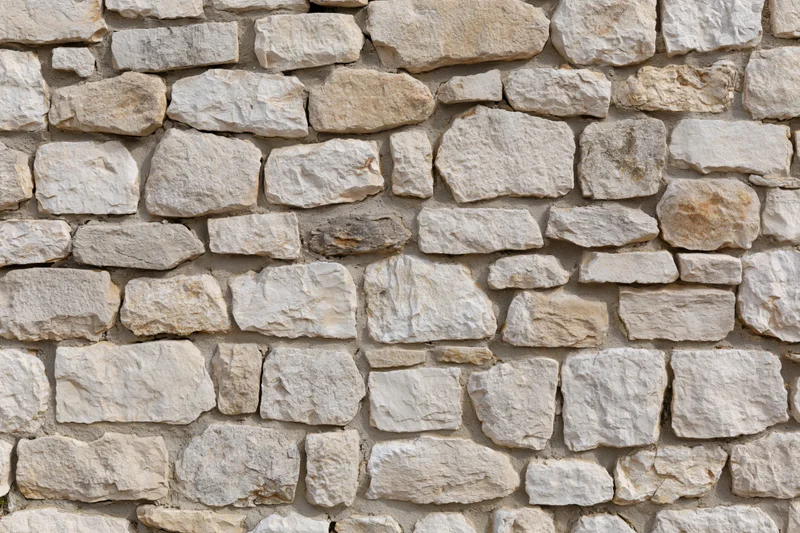 Close-up of an old rustic stone wall with uneven natural stones and mortar filling the frame