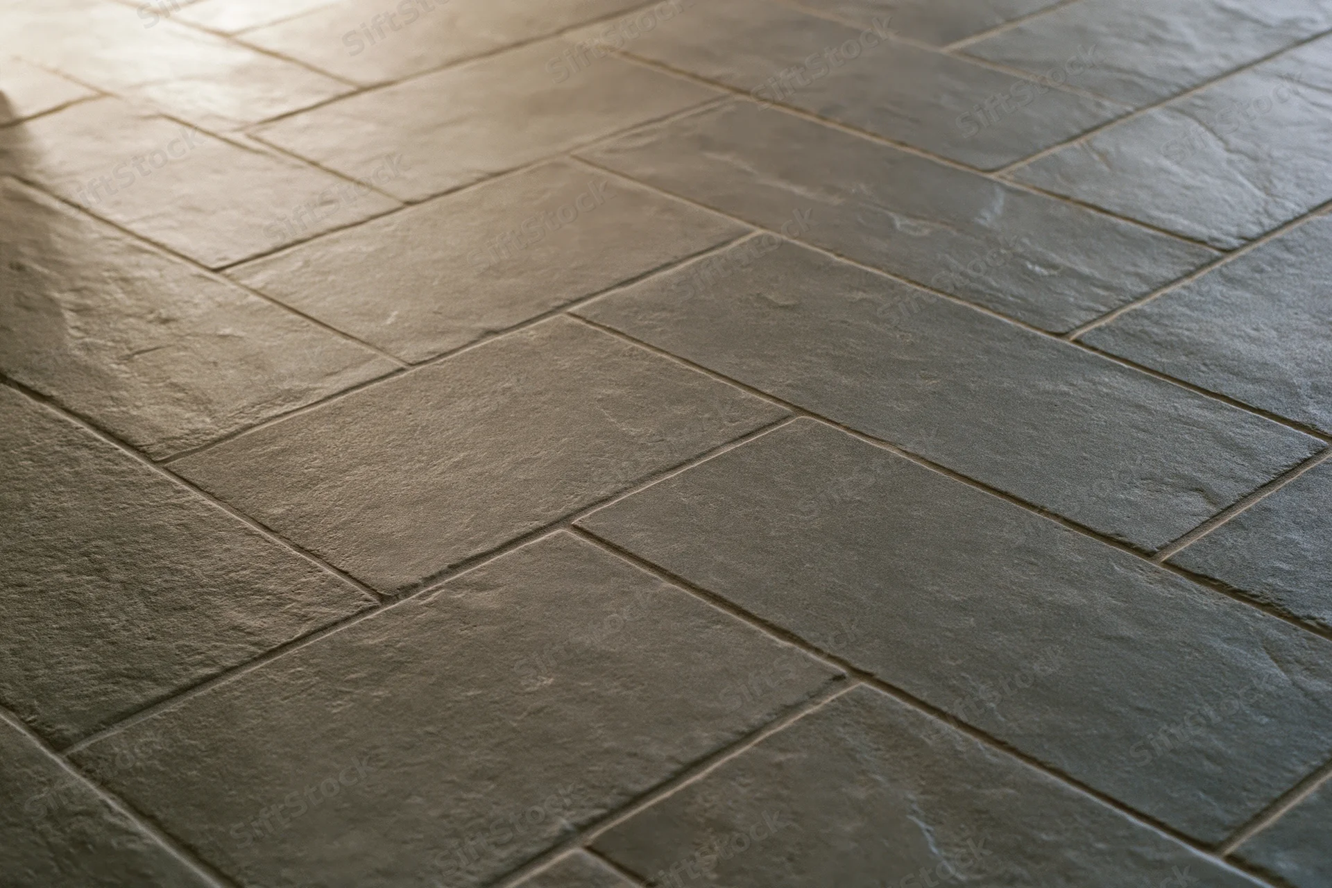 Herringbone-patterned stone tile flooring in a modern interior space