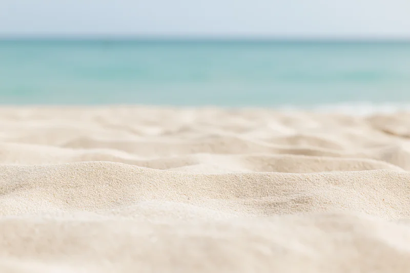 Close-up of textured pale sand on a beach with ocean in the background