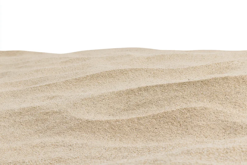 Close-up of rippled dry beach sand surface against white background