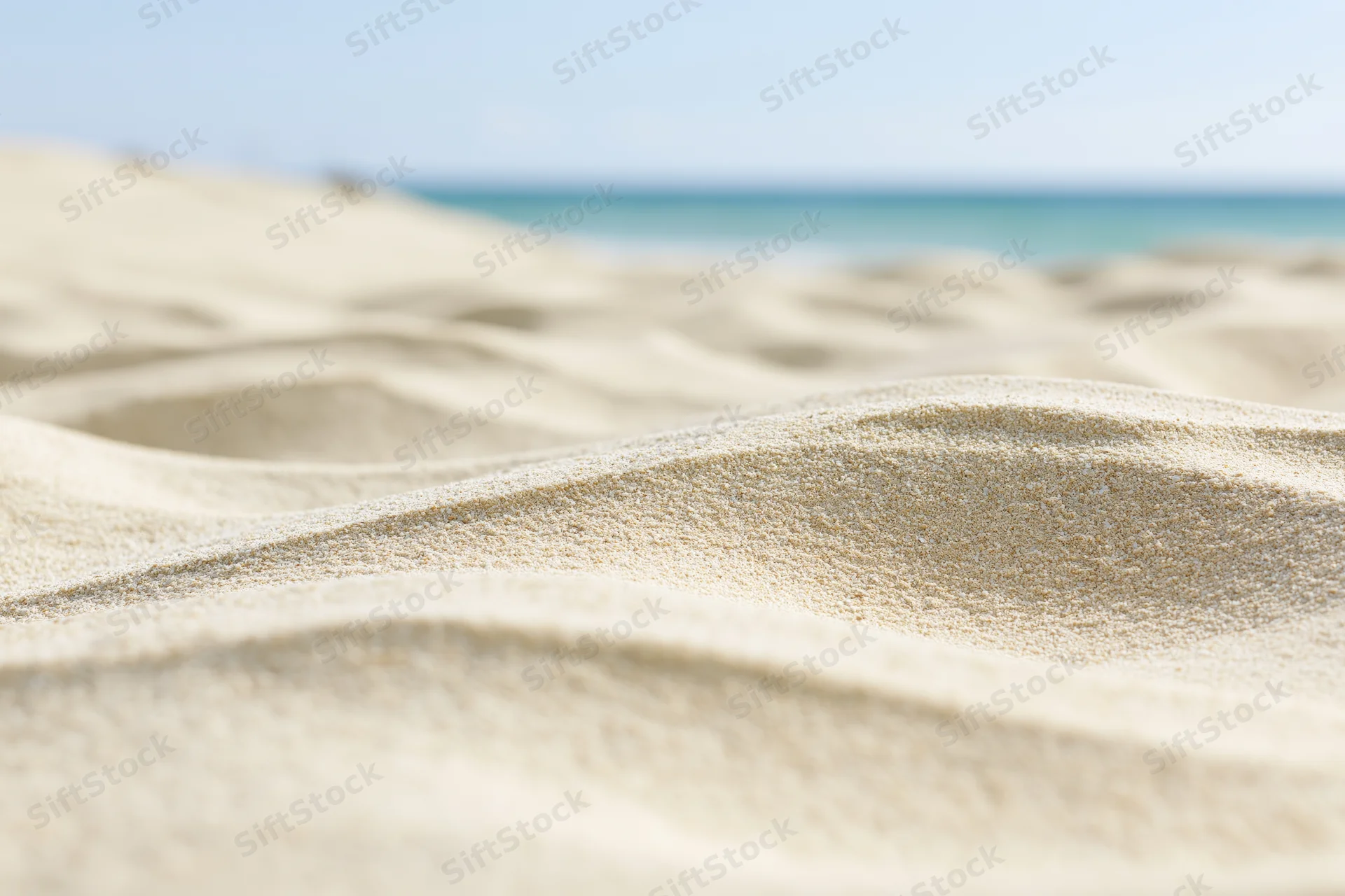 Closeup of rippled dry beach sand with ocean in the background