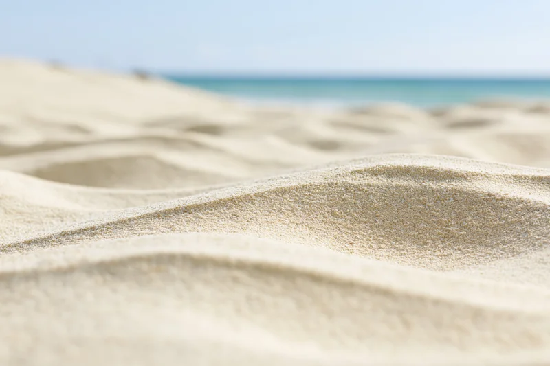 Closeup of rippled dry beach sand with ocean in the background