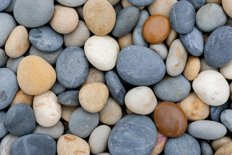 Close-up overhead view of smooth river and beach pebbles arranged in a flat lay pattern