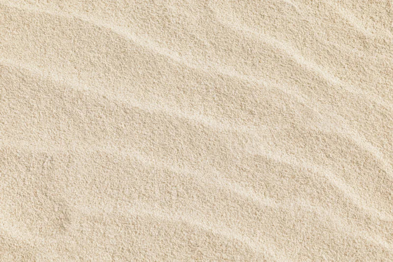 Close-up overhead view of dry beach sand surface with rippled texture