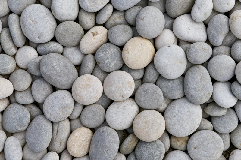 Smooth rounded river pebbles packed tightly in an overhead closeup view