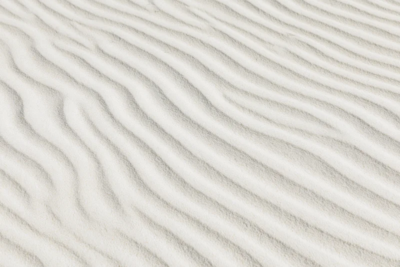 Close-up top-down view of white sand with rippled texture across the surface