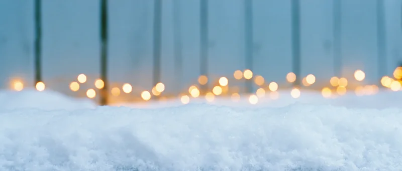 Snow surface with blurred festive lights in background