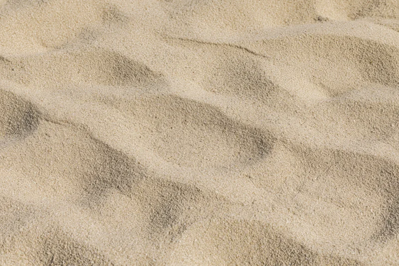 Closeup of dry beach sand surface with wind-formed ripples and undulations