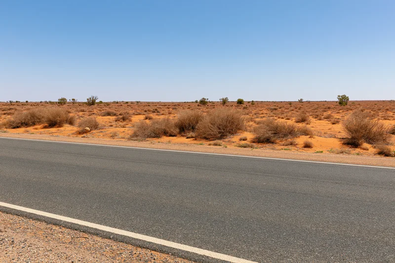 Asphalt road stretching across arid desert landscape under clear blue sky