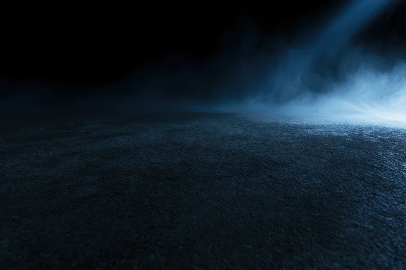 Dark concrete floor with blue light beam and fog in empty studio space
