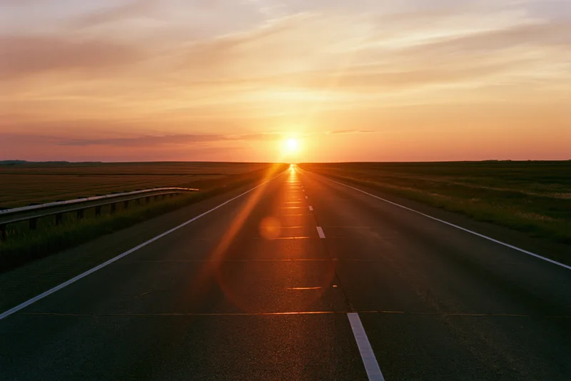 Empty two-lane asphalt highway stretching toward the horizon at sunset