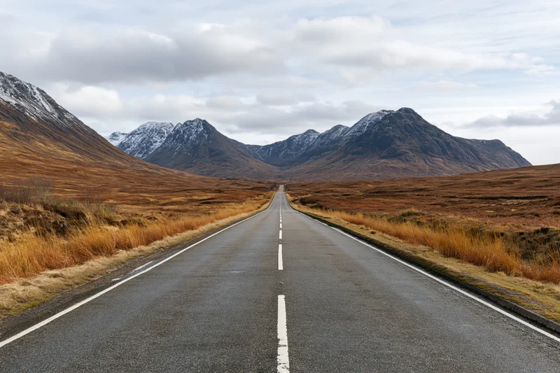 Straight asphalt road stretching through a mountain valley in the Scottish Highlands