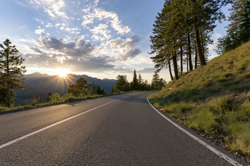 Winding asphalt road curving through mountain landscape at sunrise