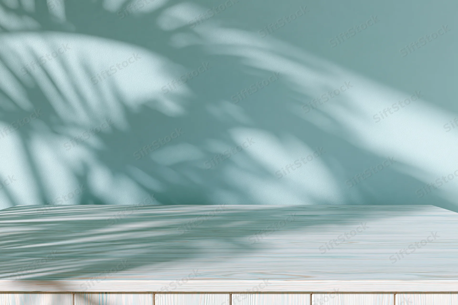 White-washed wooden tabletop with palm leaf shadows against a soft teal wall