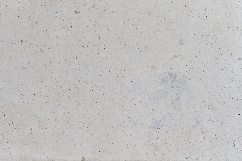 Flat concrete surface with speckled texture and faint stains, full-frame view