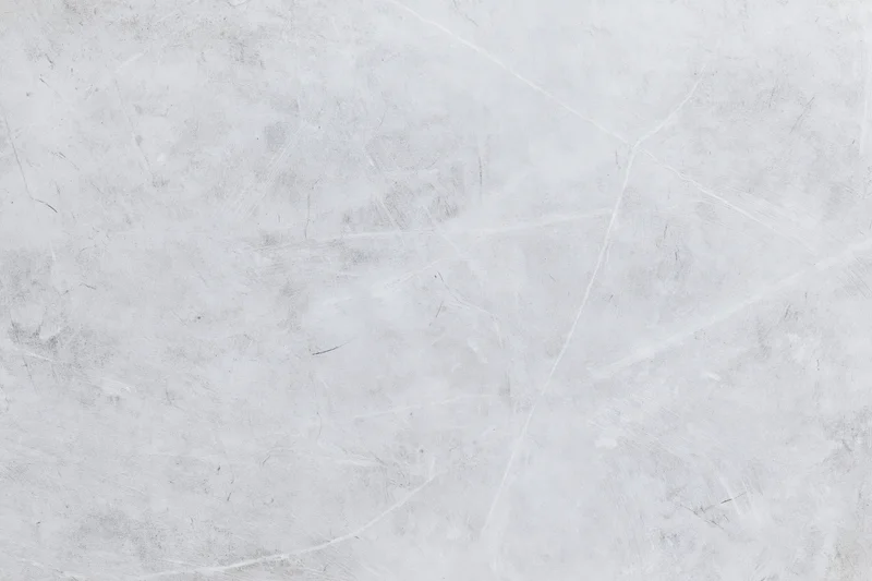 Close-up of a weathered concrete wall surface with cracks and scratches