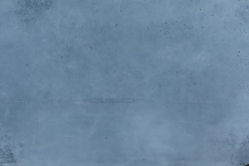 Close-up of a gray concrete wall surface with speckles and faint scratches