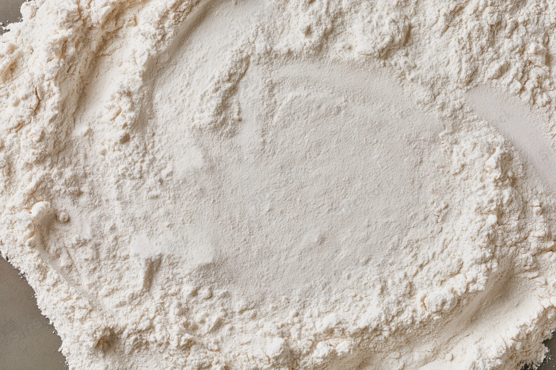 White wheat flour spread in a mound on a flat surface viewed from above