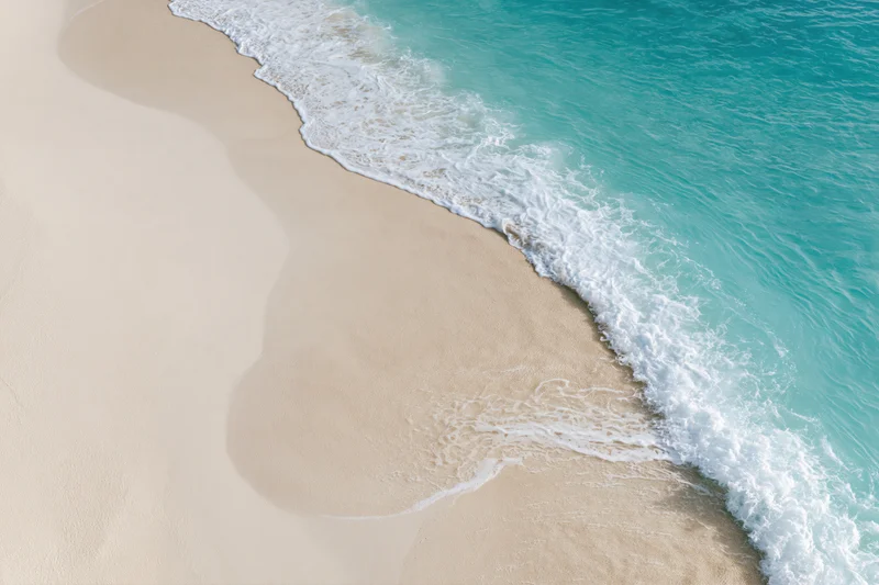 Gentle ocean wave washing onto clean white sand at the beach