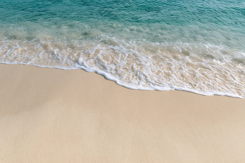 Gentle ocean wave washing over clean sandy beach