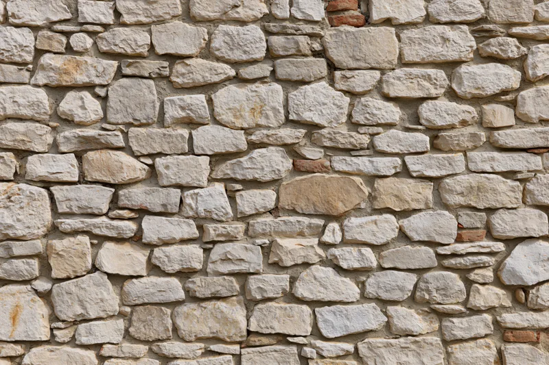 Old irregular stone wall filling the frame with natural texture and mortar joints