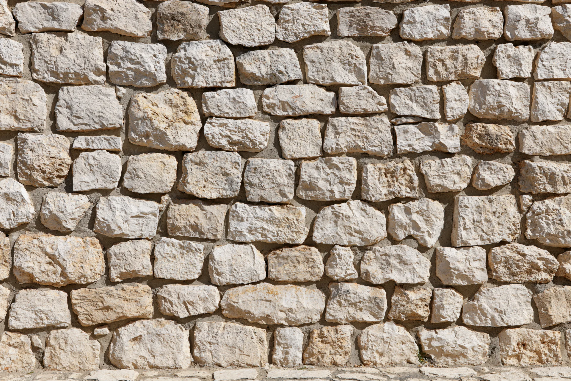 Close-up of an old rough-cut limestone rubble wall filling the frame