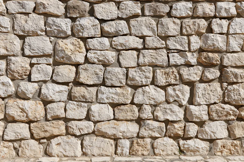 Close-up of an old rough-cut limestone rubble wall filling the frame