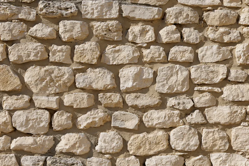 Close-up of a rough-cut limestone rubble wall with irregular stones and mortar joints