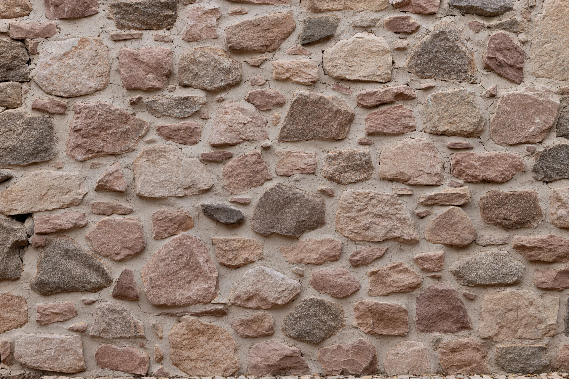Close-up of an old rubble stone wall with irregularly shaped stones set in mortar