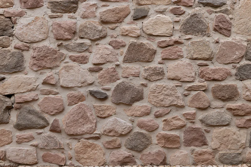 Close-up of an old rubble stone wall with irregularly shaped stones set in mortar