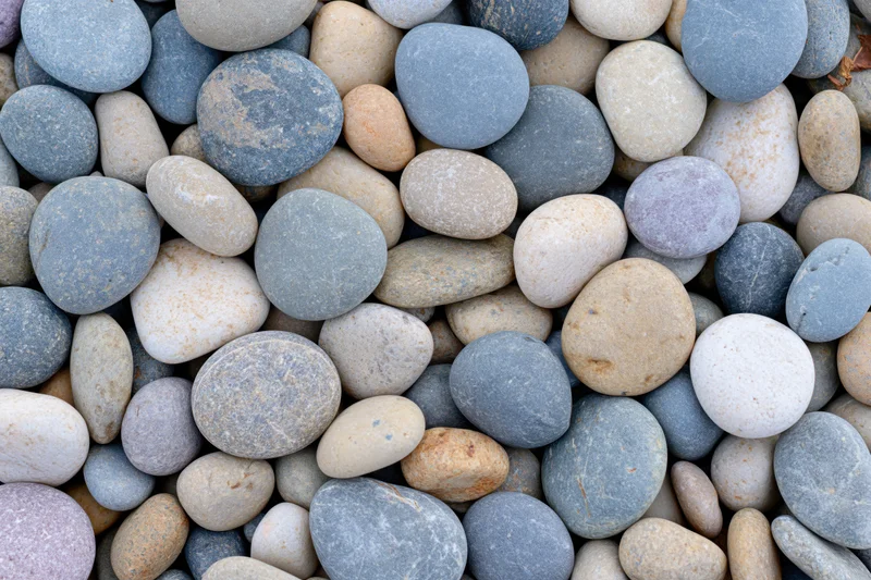 Smooth rounded pebbles scattered in a dense overhead flat lay pattern