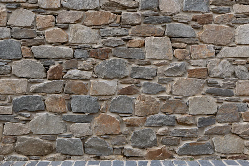 Rustic dry-stone wall made of irregularly shaped stones in natural earth tones filling the frame