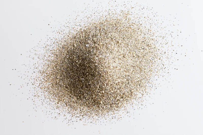 Pile of gold and silver glitter scattered on white surface
