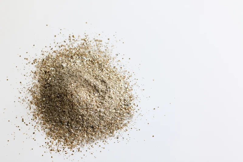 Pile of gold and silver glitter scattered on white surface with copyspace