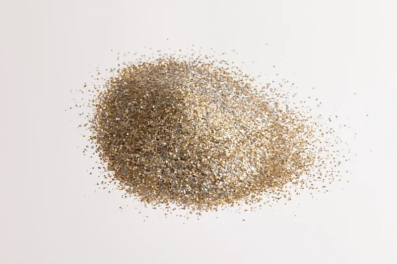 Pile of gold and silver glitter scattered on white surface