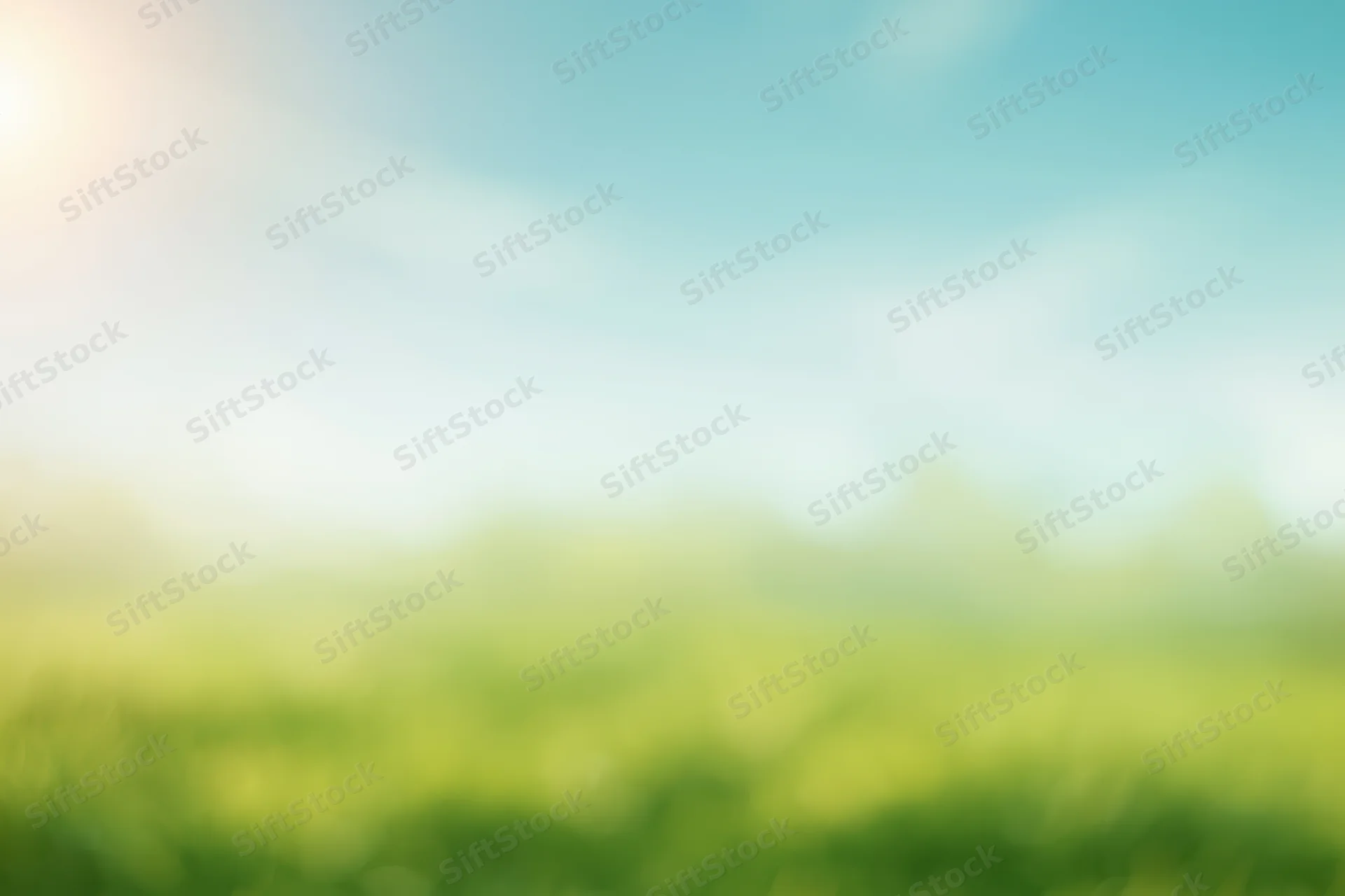 Blurred green grass field under blue sky with sunlight