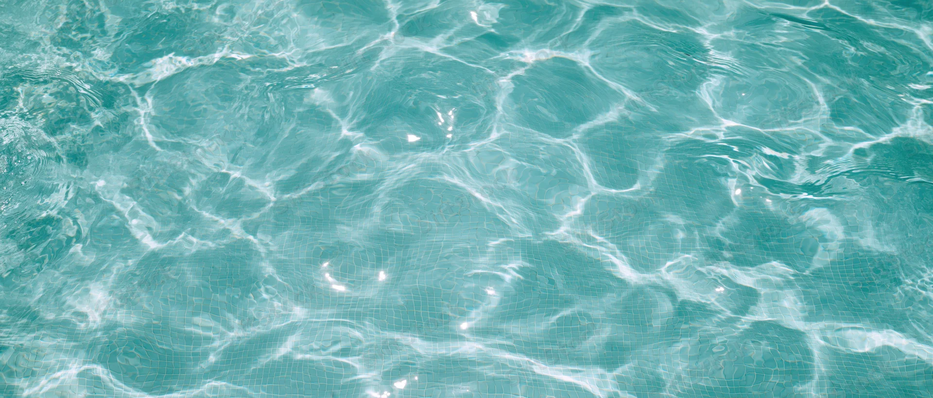 Clear turquoise water surface with gentle ripples and light reflections in a swimming pool