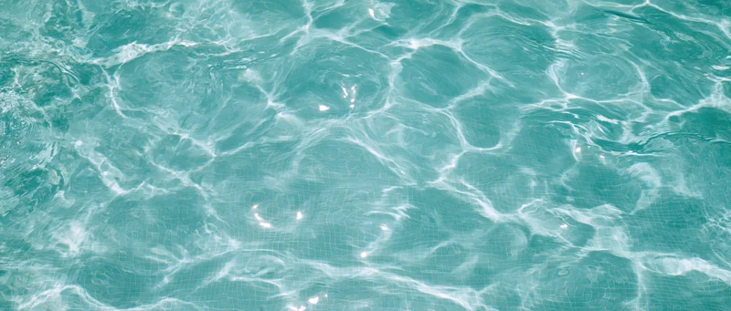 Clear turquoise water surface with gentle ripples and light reflections in a swimming pool