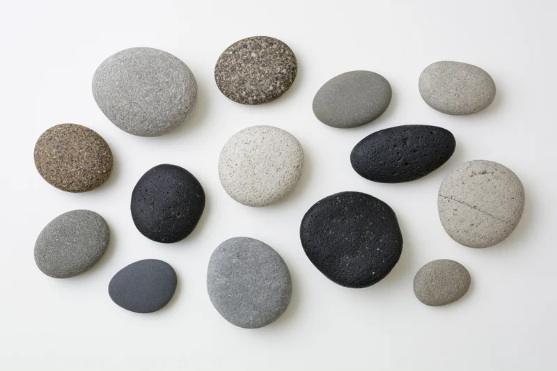 Smooth river and sea pebbles arranged in a flat lay on a white surface