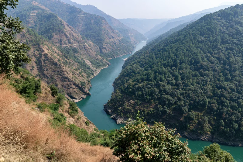 Turquoise river winding through deep canyon flanked by forested mountains