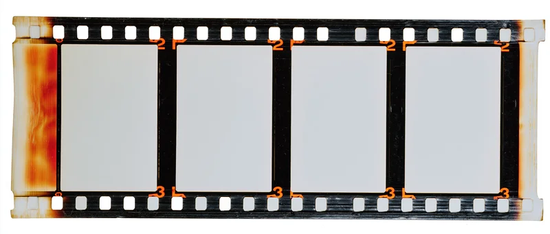 Blank 35mm film strip with four empty white frames and orange-brown stains on edges, isolated on white