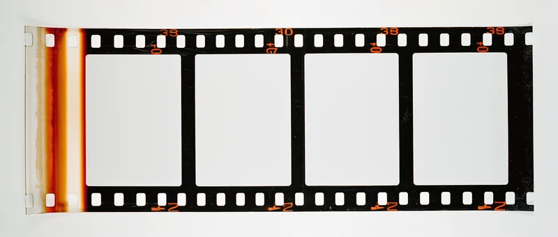 Blank 35mm film strip with four white frames and orange edge numbers on white background