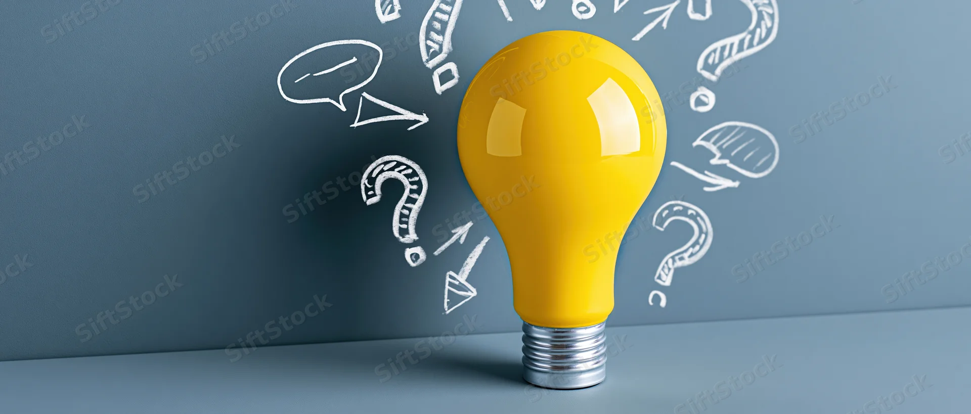 Yellow lightbulb with white sketched symbols on a blue wall surface