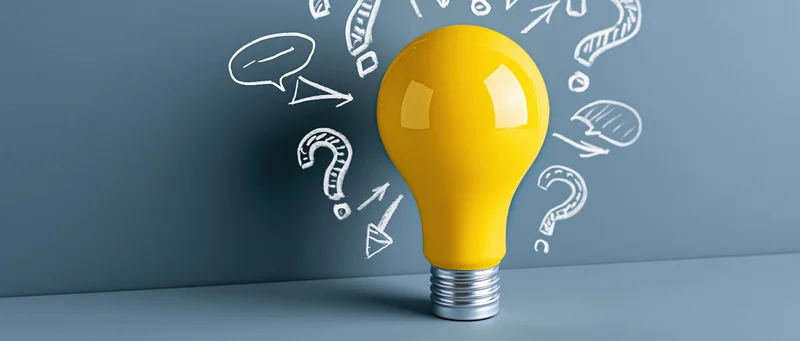 Yellow lightbulb with white sketched symbols on a blue wall surface