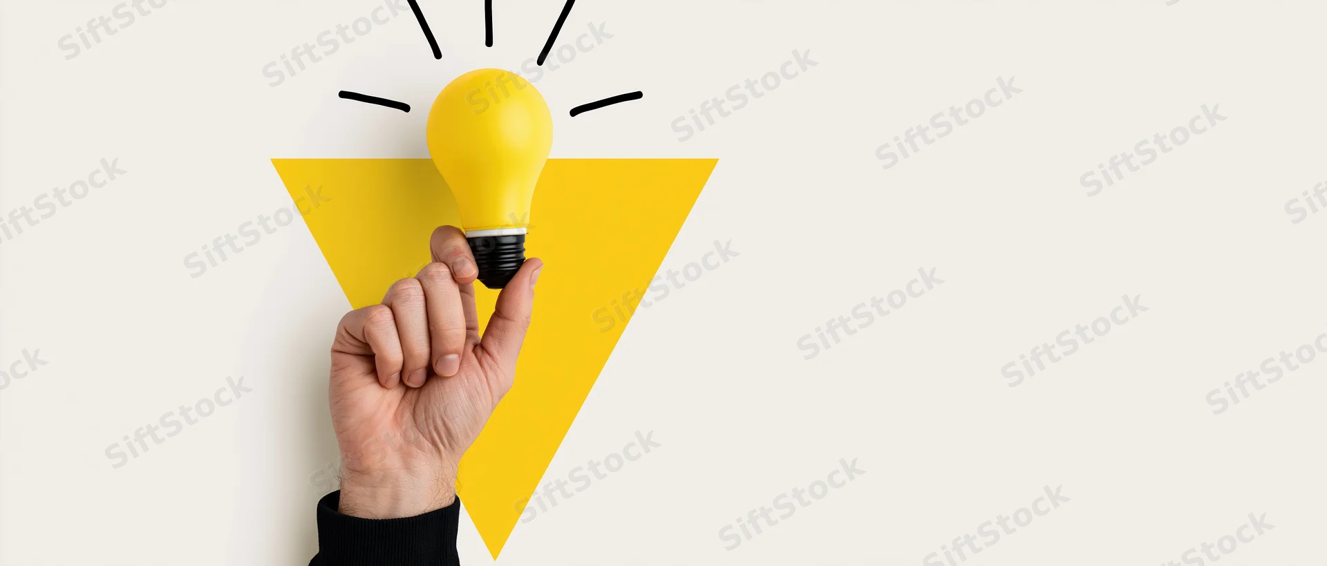 Hand holding yellow lightbulb against white background with graphic triangle and rays