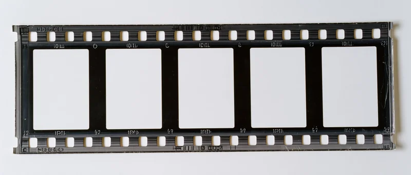Horizontal strip of 35mm film negative with five blank frames on white background