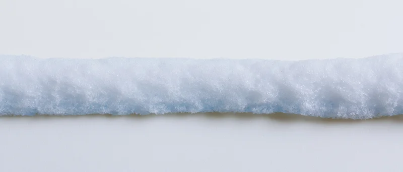 Narrow horizontal ridge of fresh snow isolated against a plain white background
